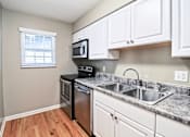 Thumbnail 8 of 25 - A kitchen with a black stove top oven and white cabinets.