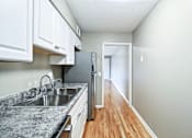 Thumbnail 10 of 25 - A kitchen with a granite countertop and white cabinets.
