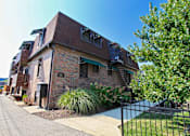 Thumbnail 1 of 25 - A brick building with a green awning and a black fence in front.
