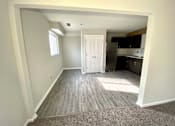 Thumbnail 10 of 28 - A room with a white door leading to a kitchen.