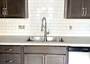 Thumbnail 26 of 28 - A kitchen with a white sink and a white dishwasher.
