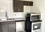 Thumbnail 20 of 28 - A kitchen with a black microwave oven on a black cabinet.