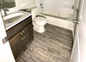 Thumbnail 25 of 28 - A white tiled bathroom with a wooden floor.