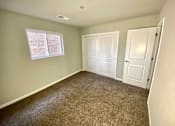 Thumbnail 18 of 28 - A room with carpeted floor, two doors, and a window with blinds.