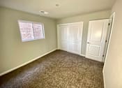 Thumbnail 6 of 28 - A room with carpeted floor, two doors, and a window with blinds.