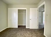 Thumbnail 23 of 28 - A room with two white doors and carpeted flooring.