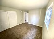 Thumbnail 21 of 28 - A room with carpeted floor, two doors, and a window.