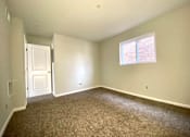 Thumbnail 19 of 28 - A room with a carpeted floor, a door, and a window with blinds.