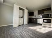 Thumbnail 16 of 28 - A kitchen with a white fridge and microwave, and a wooden floor.
