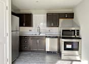 Thumbnail 13 of 28 - A kitchen with dark brown cabinets and a white tiled backsplash.