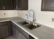 Thumbnail 15 of 28 - A kitchen with a sink and a faucet.