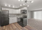 Thumbnail 1 of 10 - A kitchen with a black refrigerator, white cabinets, and a black stove top oven.