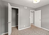 Thumbnail 6 of 10 - A room with a carpeted floor and two doors, one of which is open.