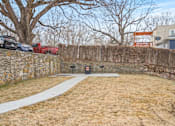 Thumbnail 10 of 10 - A backyard with a stone wall and a white pathway.