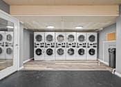 Thumbnail 7 of 10 - A laundry room with a row of washing machines.