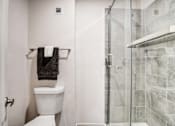 Thumbnail 24 of 25 - A white toilet sits next to a walk-in shower.