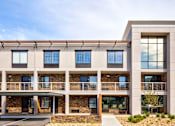 Thumbnail 5 of 25 - A modern building with a balcony and a stone wall.