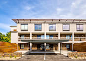 Thumbnail 4 of 25 - A modern building with a flat roof and a covered entrance.