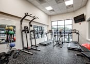 Thumbnail 13 of 25 - A gym with a variety of equipment including treadmills, weights, and exercise machines.