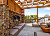 Thumbnail 8 of 25 - A patio with a stone wall and a wooden pergola.