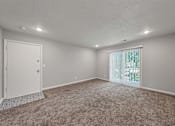 Thumbnail 7 of 20 - A room with a carpeted floor and a sliding glass door.