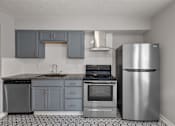 Thumbnail 17 of 20 - A kitchen with a stainless steel refrigerator, oven, and cabinets.