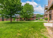 Thumbnail 2 of 39 - a grassy area with trees and buildings in the background