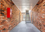 Thumbnail 6 of 39 - a long corridor with brick walls and a staircase in the middle