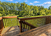 Thumbnail 1 of 11 - A wooden deck overlooks a grassy area with trees.