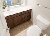 Thumbnail 8 of 11 - A white toilet sits in a bathroom next to a sink and a mirror.