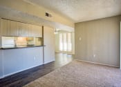 Thumbnail 4 of 28 - an empty living room with a kitchen and a counter top