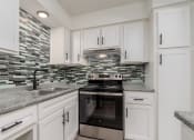 Thumbnail 1 of 8 - a kitchen with white cabinets and a stove and sink
