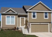 Thumbnail 1 of 25 - a tan house with a garage door and a driveway