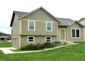 Thumbnail 1 of 21 - a tan house with a lawn and a sidewalk