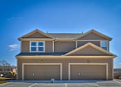 Thumbnail 1 of 14 - a tan house with two garage doors