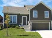 Thumbnail 3 of 25 - a brown house with a garage door