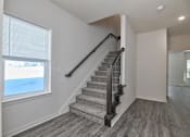 Thumbnail 27 of 32 - A staircase with a metal railing leads up to a window.