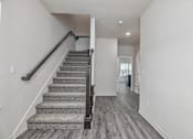Thumbnail 2 of 32 - A staircase with a carpeted runner and wooden handrail.