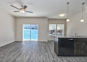 Thumbnail 5 of 32 - A spacious room with a ceiling fan and a kitchen area with a sink.
