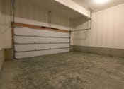 Thumbnail 12 of 14 - a garage door in a room with a cement floor