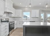 Thumbnail 12 of 52 - A modern kitchen with white cabinets and a large island.
