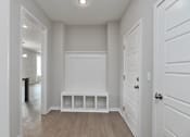 Thumbnail 14 of 52 - A white hallway with a bench and a door.
