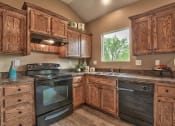 Thumbnail 21 of 25 - a kitchen with wooden cabinets and black appliances