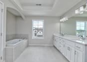 Thumbnail 18 of 52 - A white bathroom with a tub, sink, and mirror.