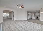 Thumbnail 9 of 52 - A spacious living room with a ceiling fan and carpeted floor.