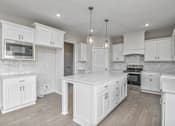 Thumbnail 10 of 52 - A modern kitchen with white cabinets and a wooden floor.
