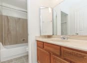 Thumbnail 7 of 13 - A bathroom with a wooden vanity and a white bathtub.