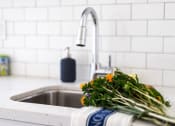Thumbnail 27 of 33 - a kitchen sink with a bunch of flowers on the counter