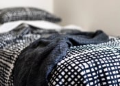 Thumbnail 18 of 33 - a bed with a checkered comforter and a black and white blanket