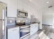 Thumbnail 3 of 32 - A modern kitchen with white appliances and cabinets.